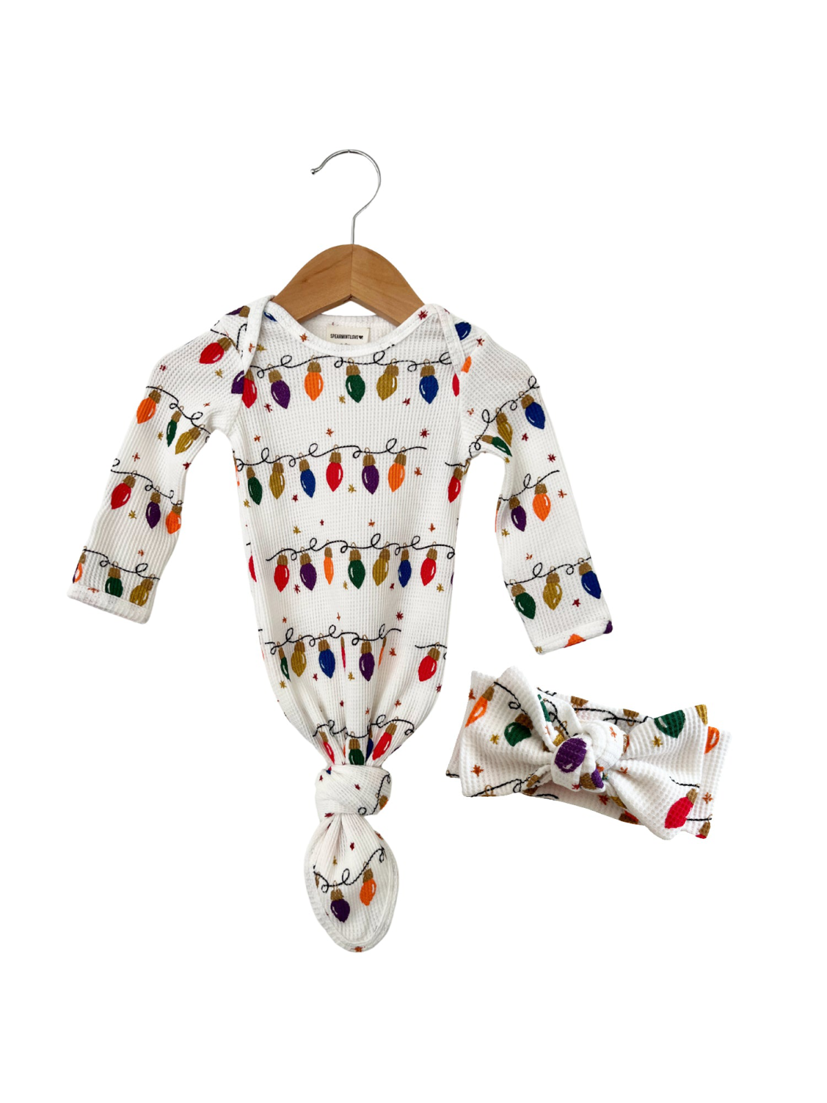 White baby outfit with colorful holiday light print, featuring a knotted gown and matching headband.