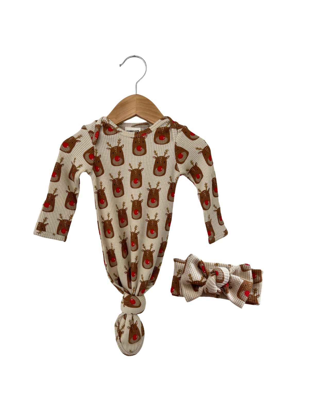Reindeer-patterned infant onesie and matching headband on a wooden hanger.
