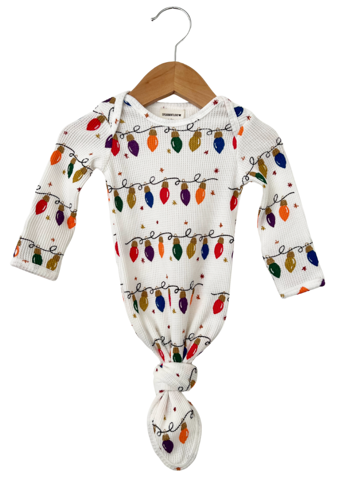 White baby outfit with colorful holiday lights print, featuring a knotted bottom and long sleeves on a wooden hanger.