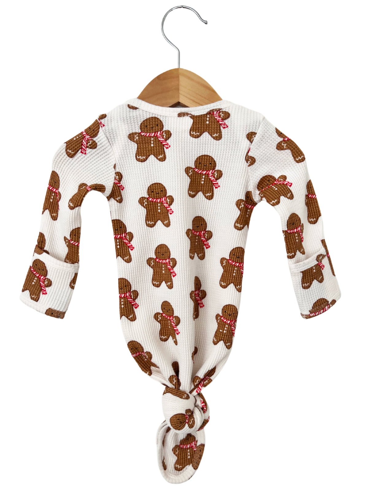 Brown gingerbread-themed onesie hanging on a wooden hanger against a white background.