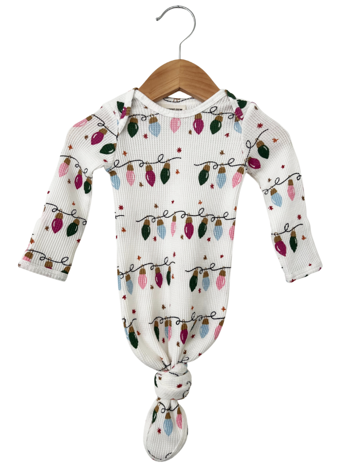 White baby onesie with colorful Christmas lights pattern, hanging on a wooden hanger.