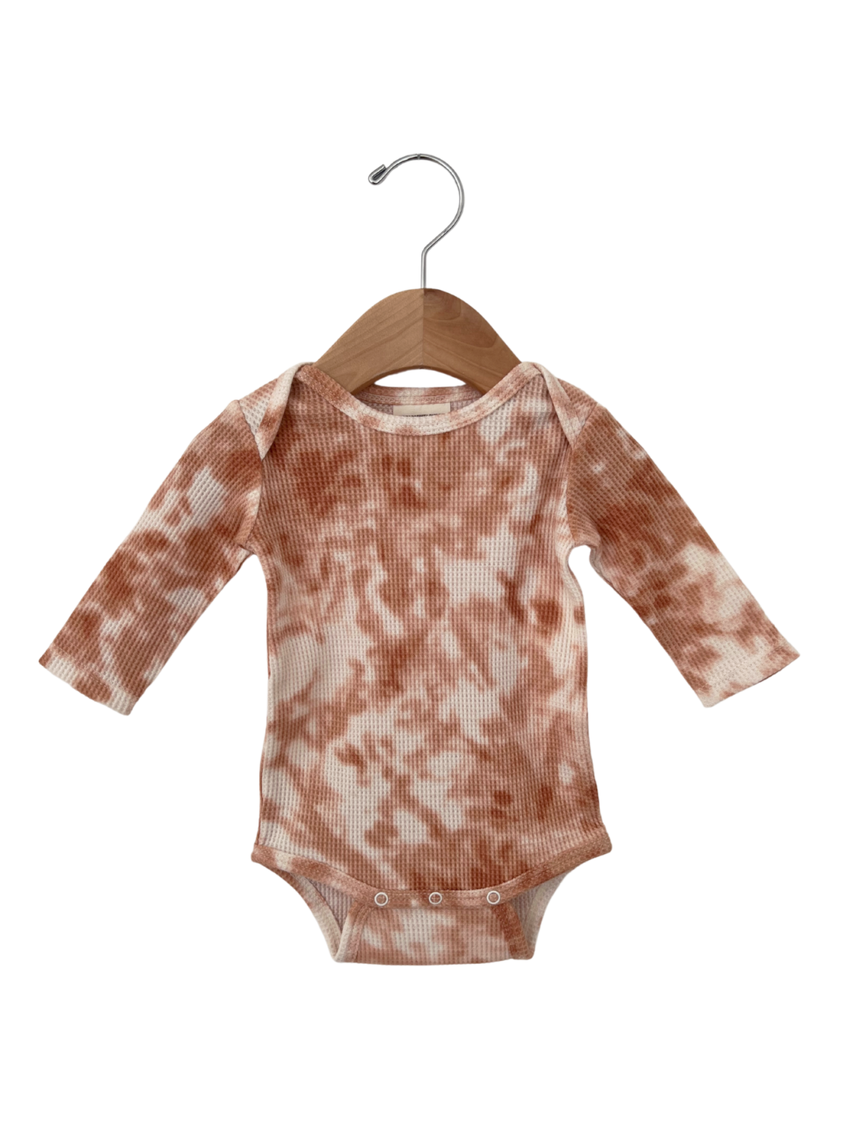 Long-sleeve tie-dye baby onesie in warm tones, hanging on a wooden hanger.