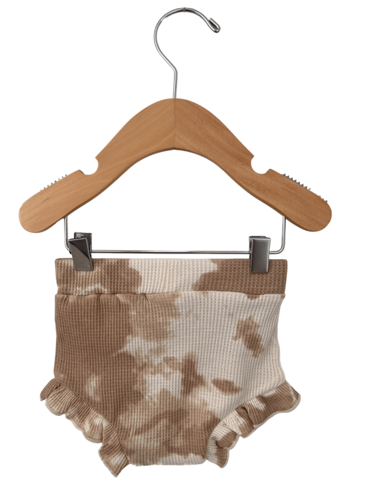 Tan and white tie-dye baby shorts with ruffled edges, hanging on a wooden clothes hanger.