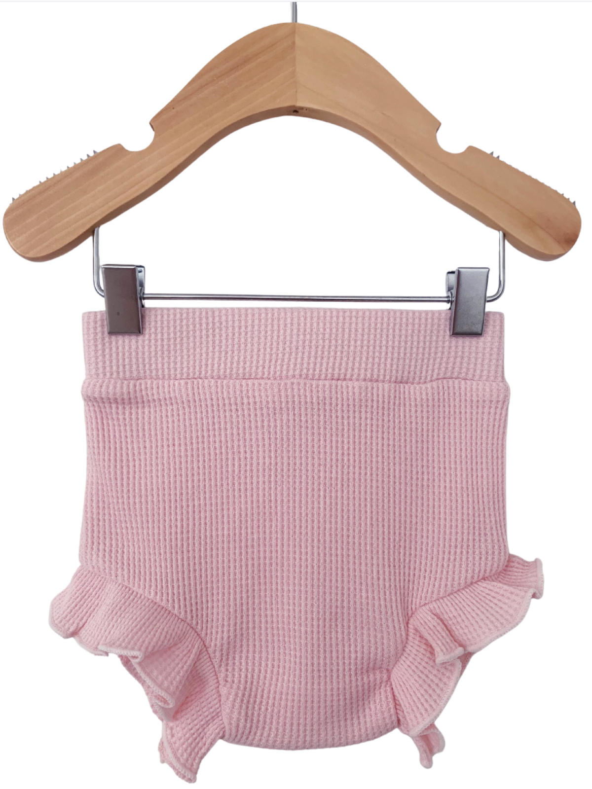 Pink knitted baby bloomer with ruffled edges, hanging on a wooden hanger.