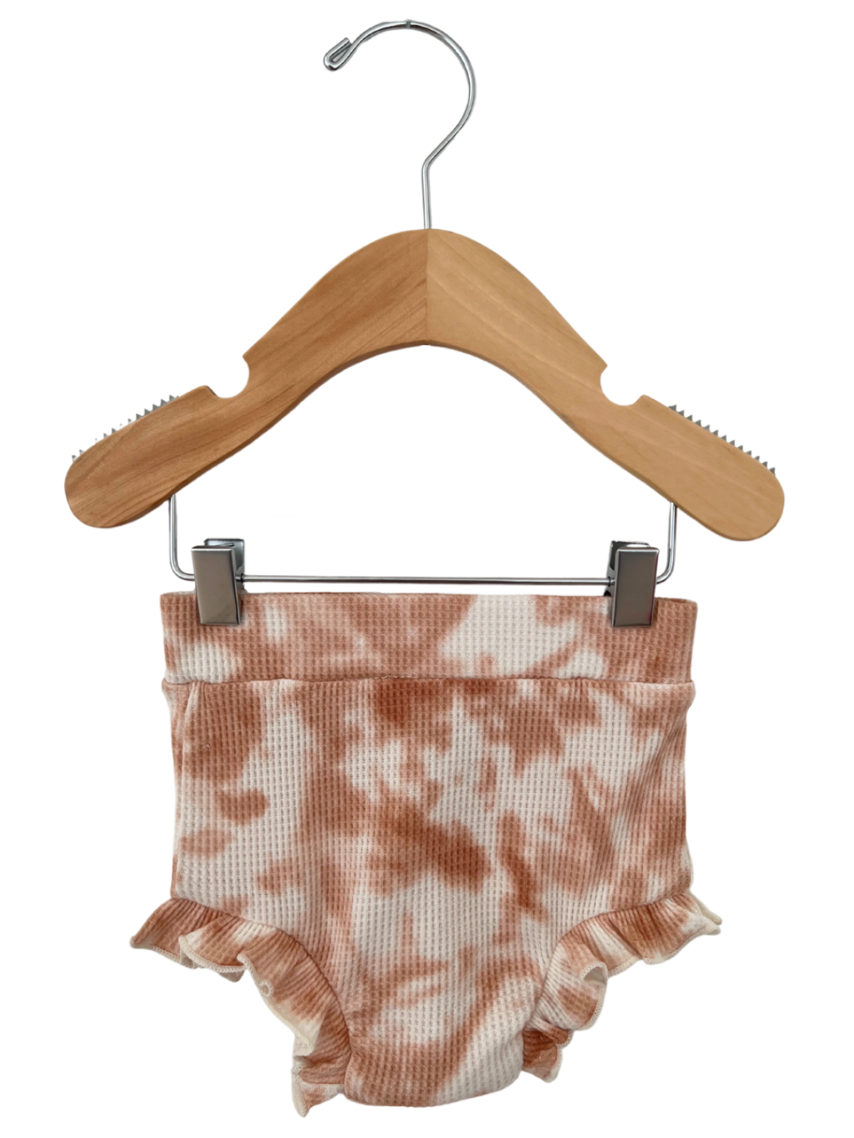Brown and cream tie-dye ruffled baby shorts on a wooden hanger.