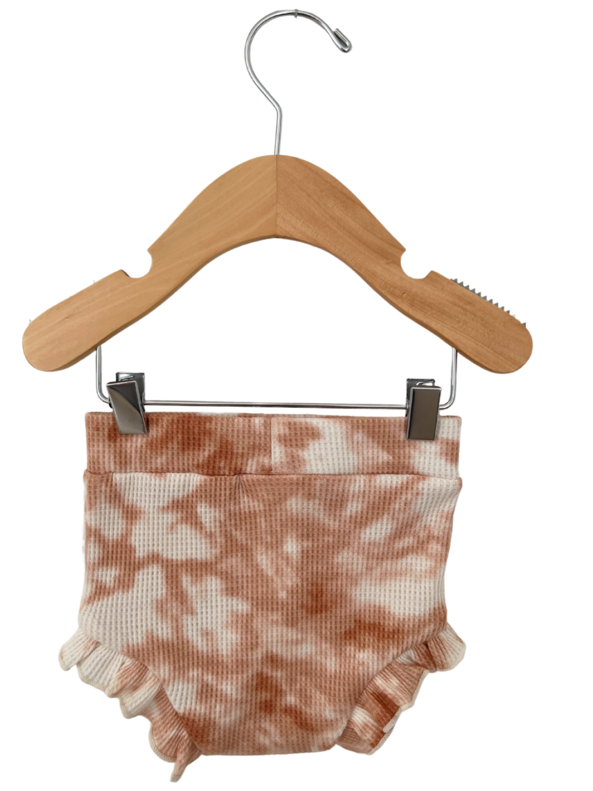 Peach tie-dye baby shorts hanging on a wooden hanger against a white background.