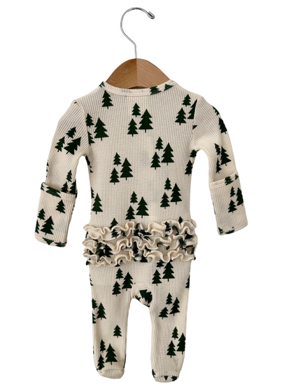 Cream-colored infant onesie with green tree print and ruffled waistband, hanging on a wooden hanger.