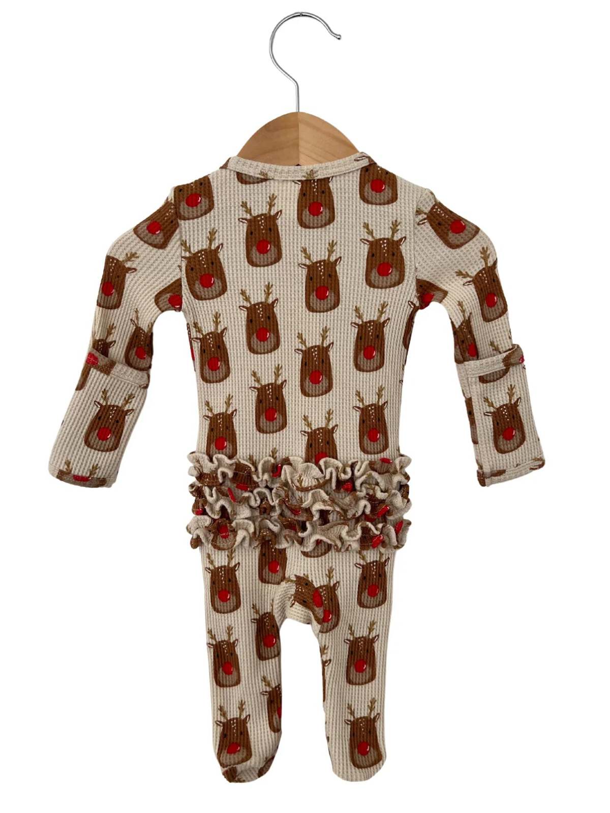 Cream-colored onesie with reindeer pattern and ruffled waist, displayed on a wooden hanger.