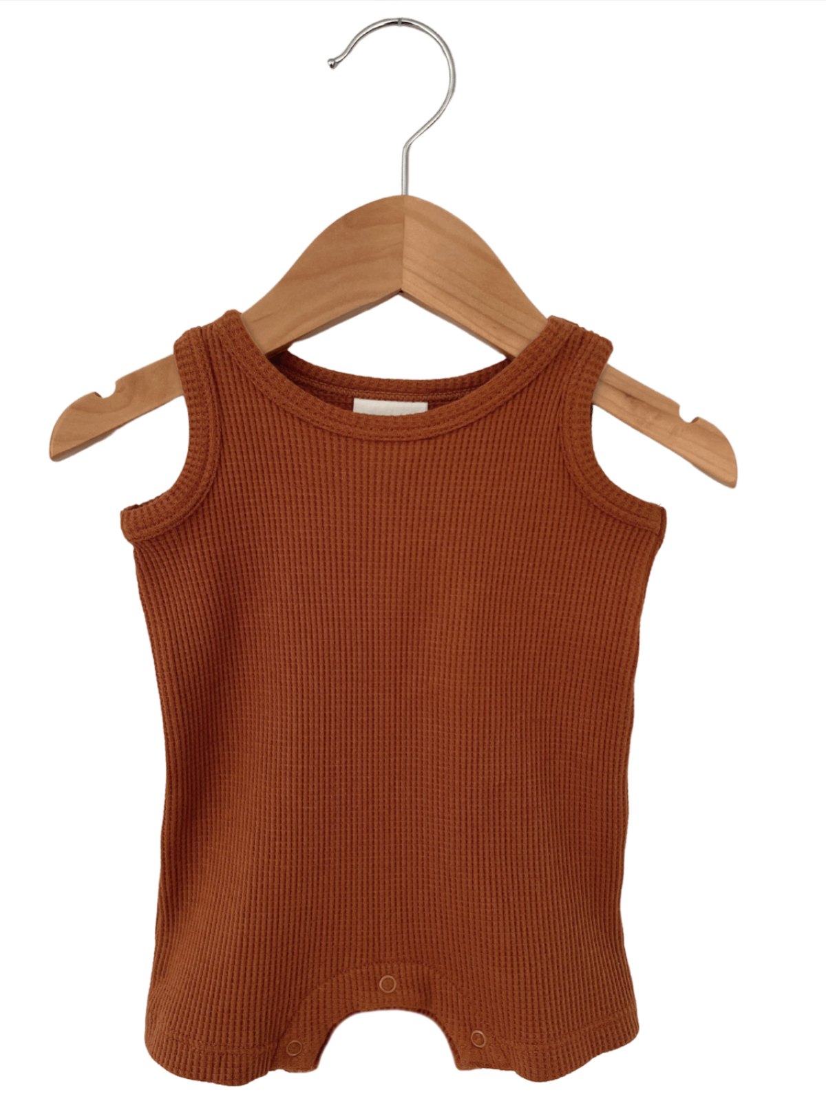Rust-colored infant tank top with ribbed texture hanging on a wooden hanger.