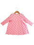 Pink dress with long sleeves and red heart patterns, hanging on a wooden hanger.