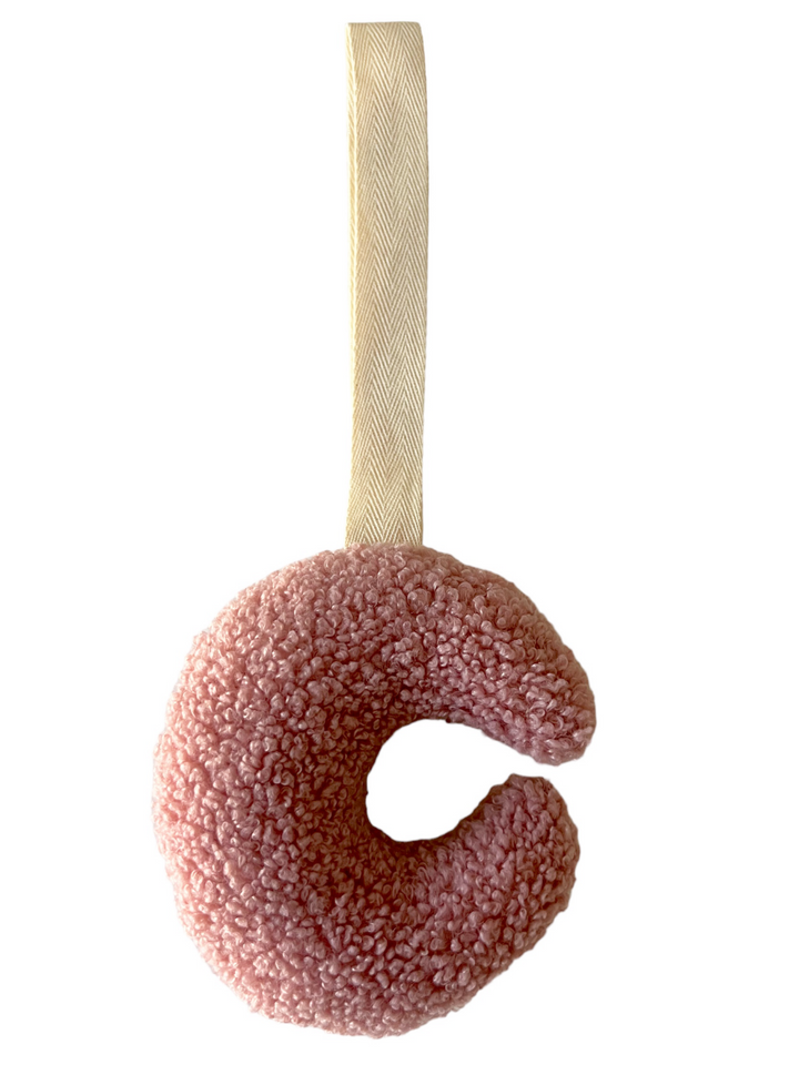Pink textured toy in a circular shape, with a cream-colored hanging loop.