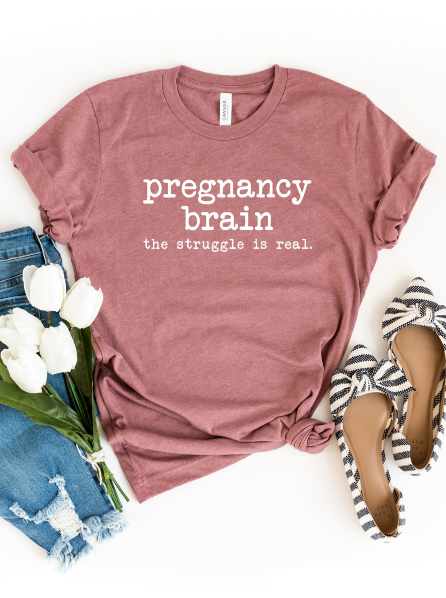 Maroon t-shirt with text "pregnancy brain the struggle is real," paired with jeans, flowers, and striped shoes.