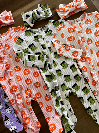 Colorful Halloween-themed toddler onesies with matching headbands featuring pumpkins and monsters.