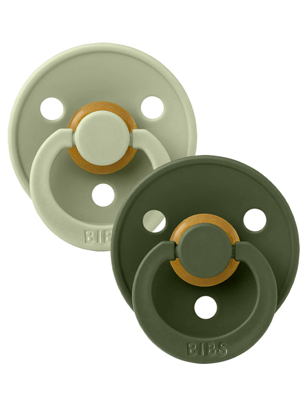 Two baby pacifiers in muted green tones with a gold accent, showcasing a modern design by BIBS.