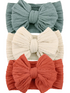 Three textured fabric headbands in teal, cream, and rust colors, featuring large bows.