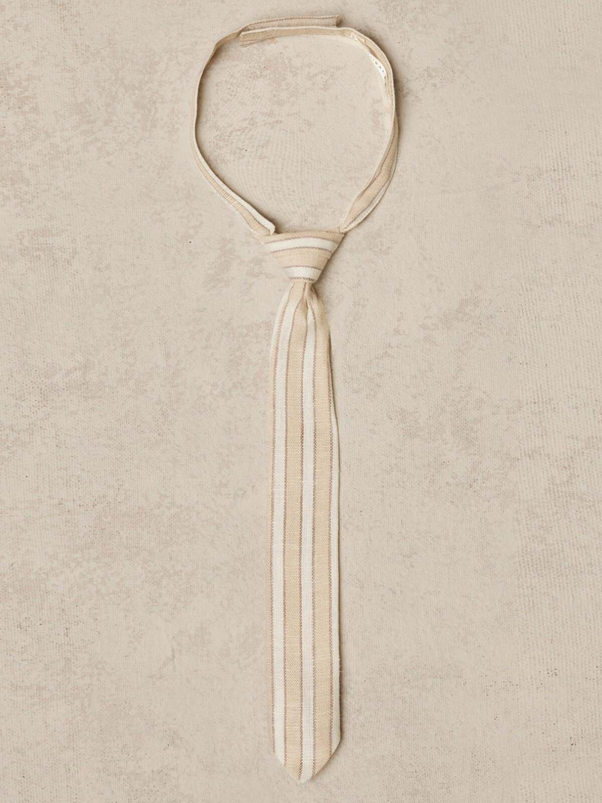 Beige striped tie displayed on a textured background.
