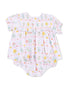 Floral baby romper with pink background and colorful flowers, featuring smocked yoke and ruffled sleeves.