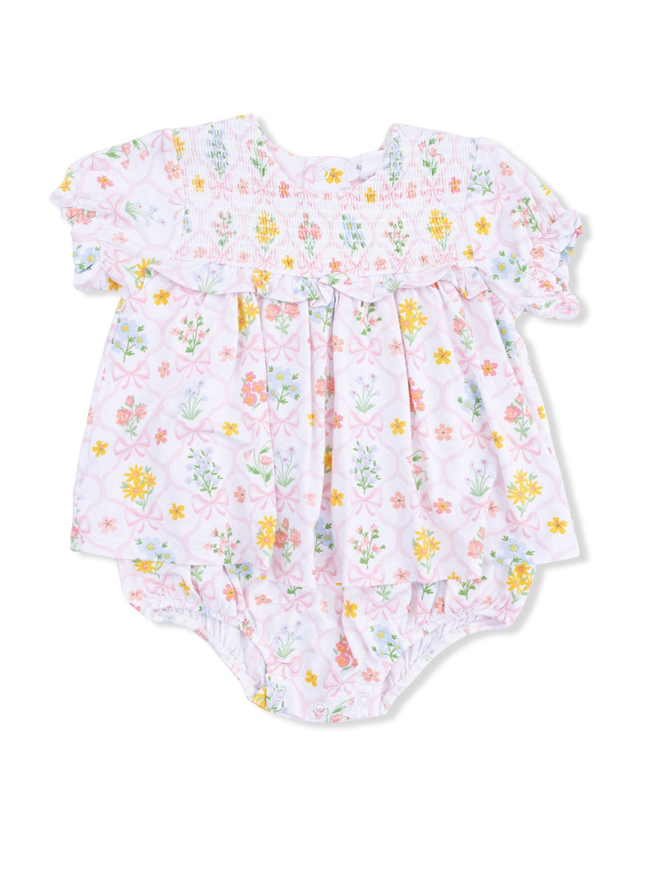 Floral baby romper with pink background and colorful flowers, featuring smocked yoke and ruffled sleeves.