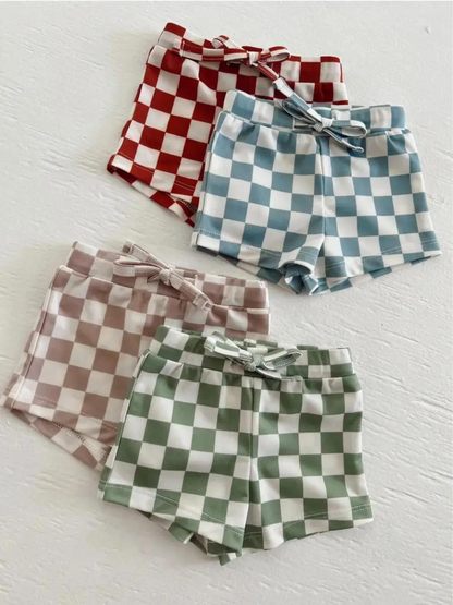 Four pairs of checkered shorts in red, blue, brown, and green on a light background.