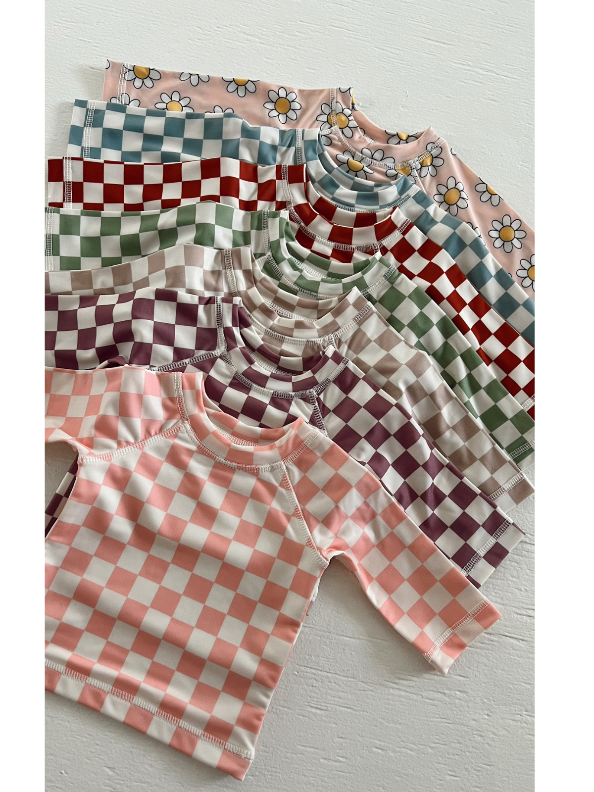 Colorful patterned shirts in various designs, including checks and floral prints, arranged neatly on a light background.