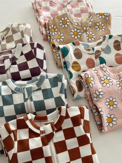 Colorful children's pajamas with various patterns, including checks, daisies, and Easter eggs, neatly folded.