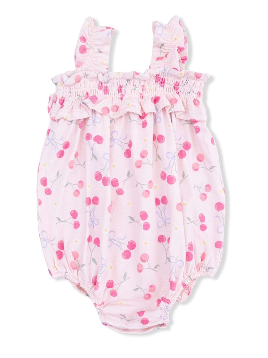 Light pink baby romper with cherry and floral patterns, featuring ruffled straps and elastic leg openings.