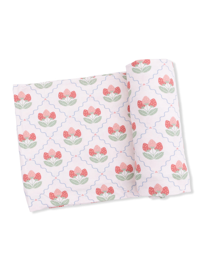 Floral fabric with pink strawberries and green leaves on a white background, rolled and flat.