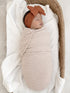 Newborn wrapped in a striped blanket, peacefully sleeping in a cozy basket with a soft knit blanket.