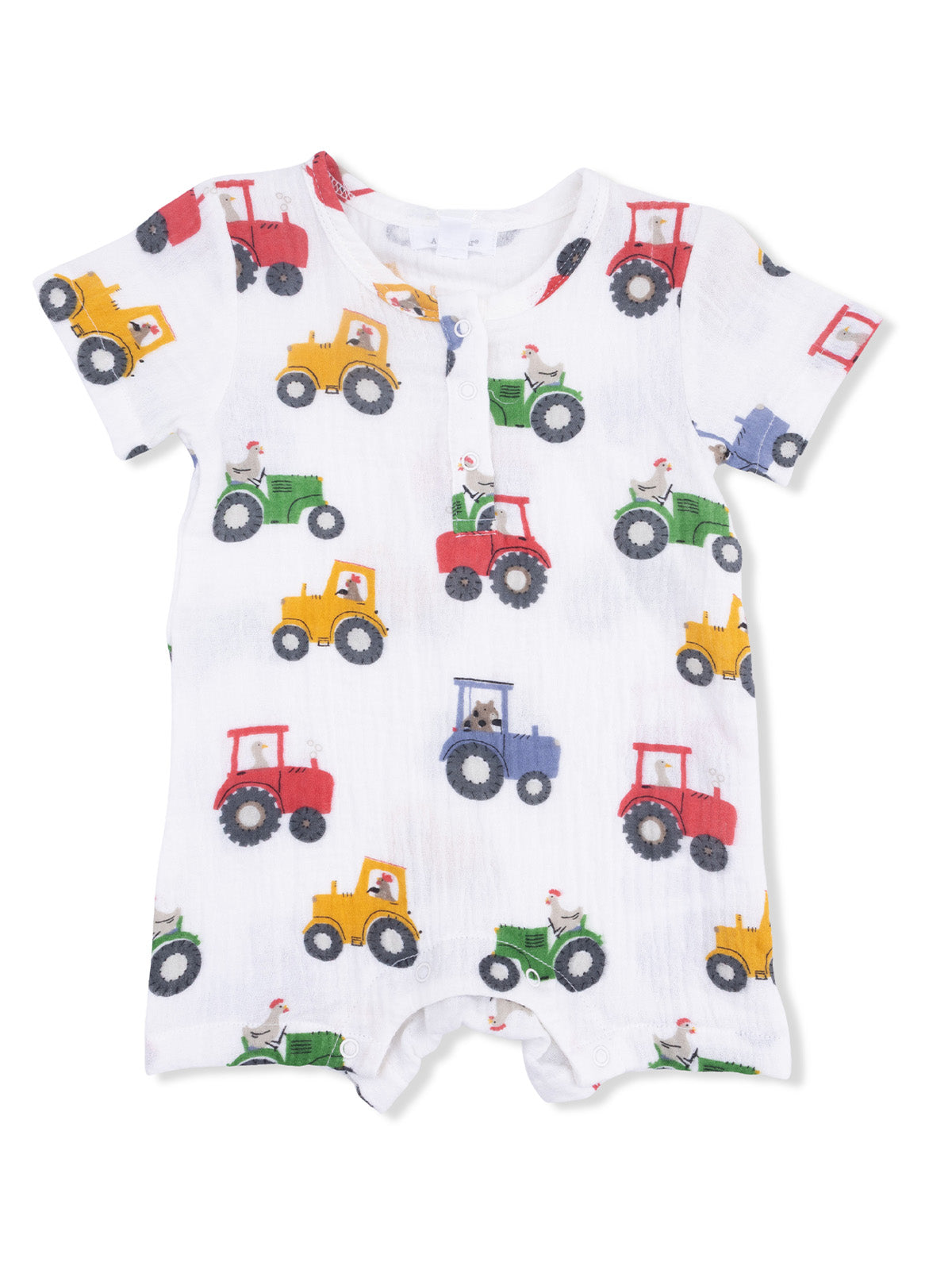 White baby romper with colorful tractor prints in yellow, green, red, and blue on a soft fabric background.