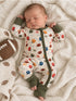 Infant sleeping peacefully in a football-themed onesie on a cozy blanket with a soft football toy nearby.