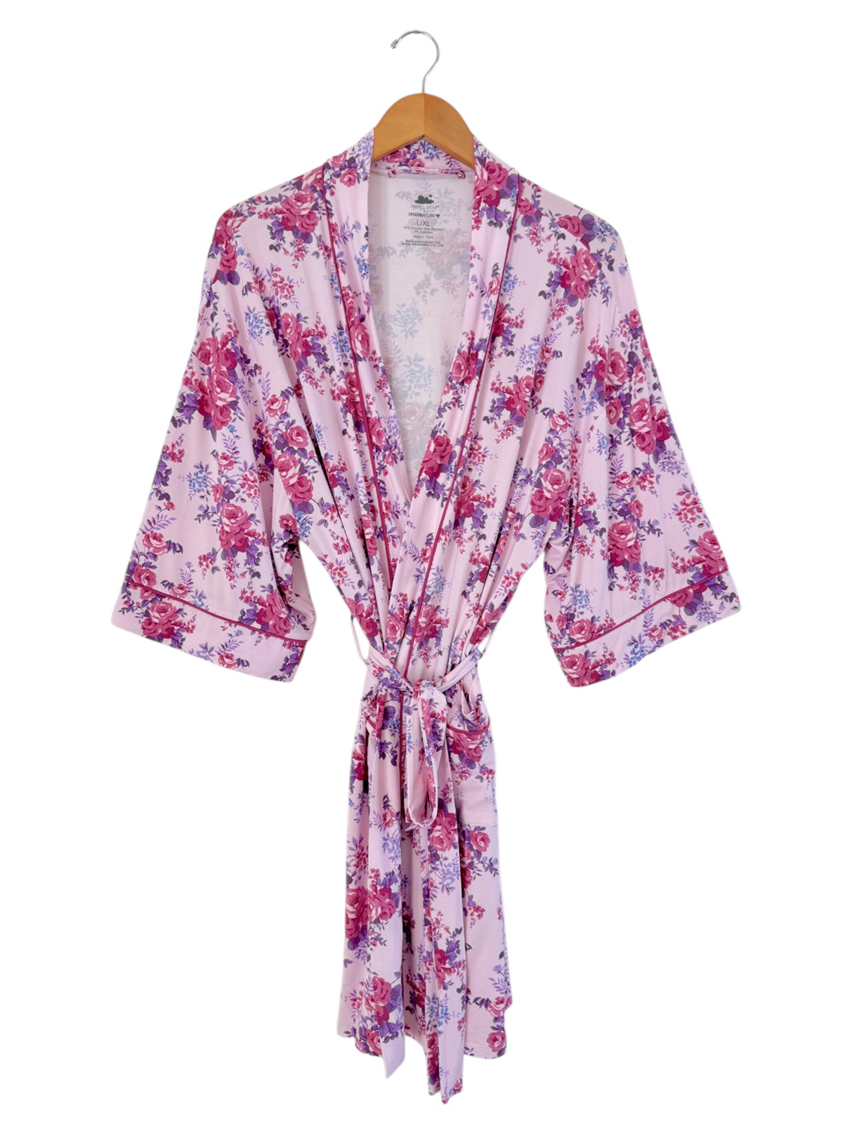 Floral pink robe with wide sleeves and a tie belt, displayed on a wooden hanger.