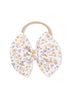 Floral fabric hair bow on a beige elastic band, featuring yellow flowers on a white background.