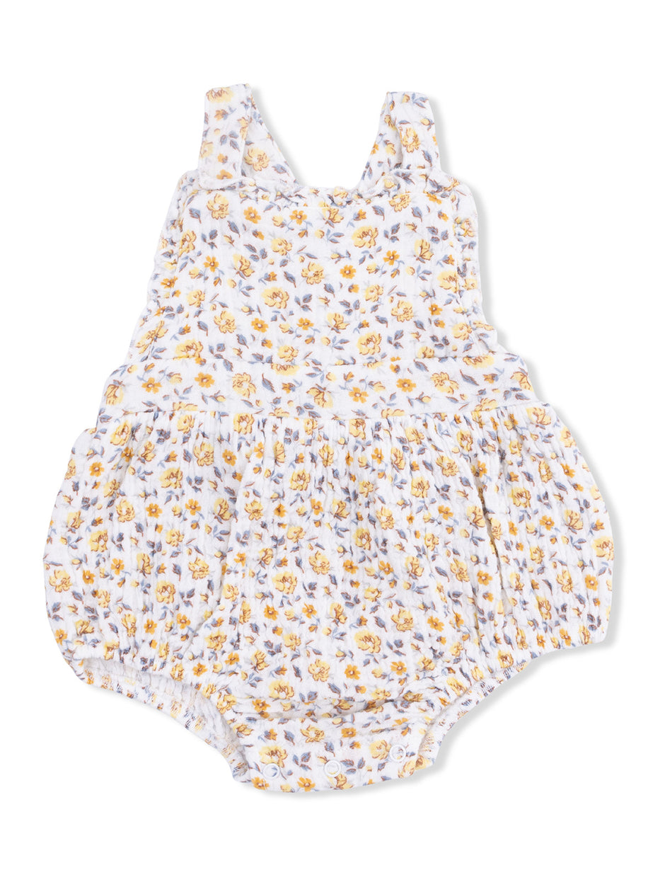 Floral infant romper with yellow and purple flowers on a white background, featuring ruffled straps and gathered bottom.