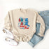 Beige sweatshirt with "Boom Boom Baby" design, paired with light jeans and white sneakers. Ideal for casual wear.