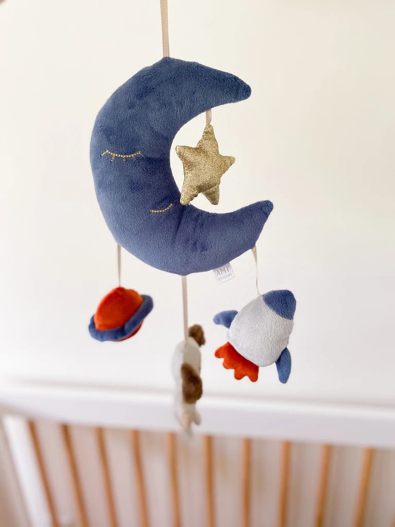 Plush mobile featuring a blue crescent moon, a gold star, and hanging space-themed toys.