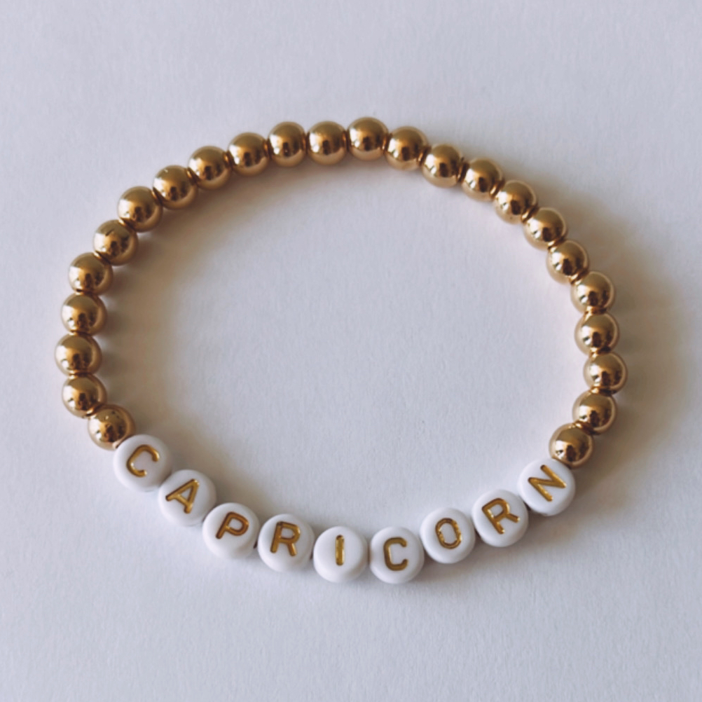 Gold and white bead bracelet with the word "CAPRICORN" spelled out.