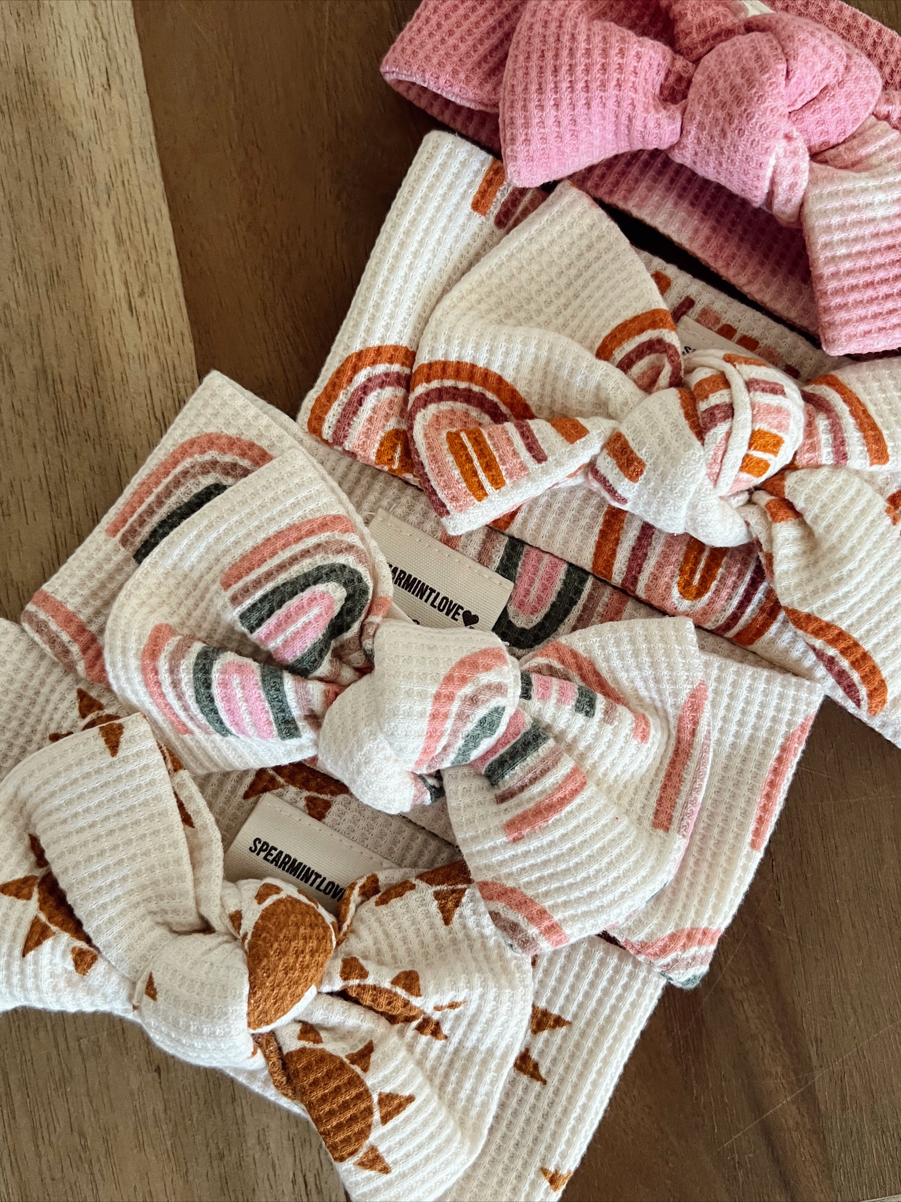 Colorful baby headbands with bows, featuring various patterns, displayed on a wooden surface.