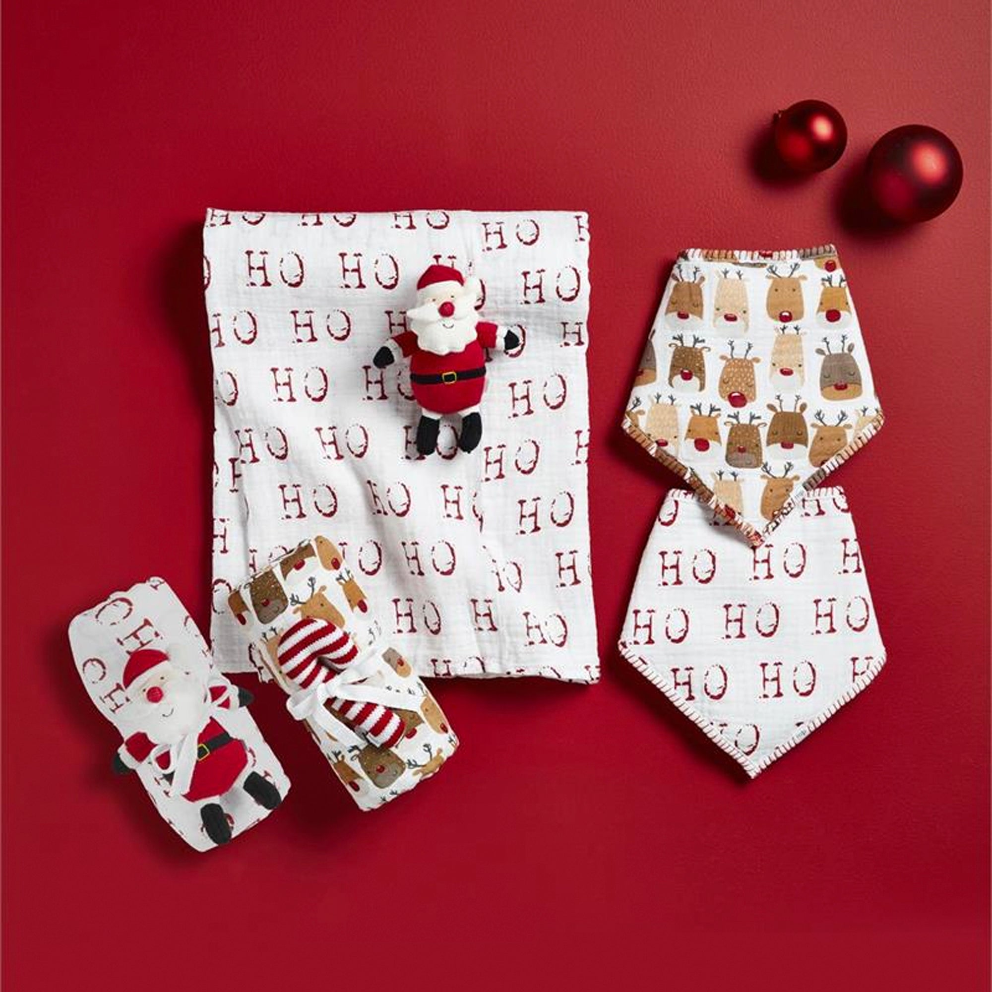 Holiday-themed napkins, featuring Santa and reindeer designs, on a red background with festive ornaments.